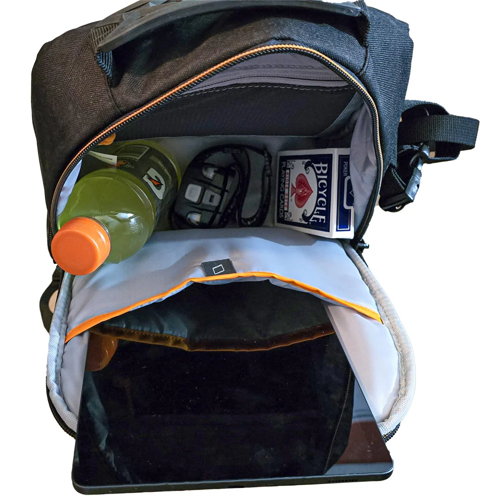 The open top compartment of the sling bag holding a water bottle, car keys, sunglasses, and a deck of playing cards, with a tablet in the slot below