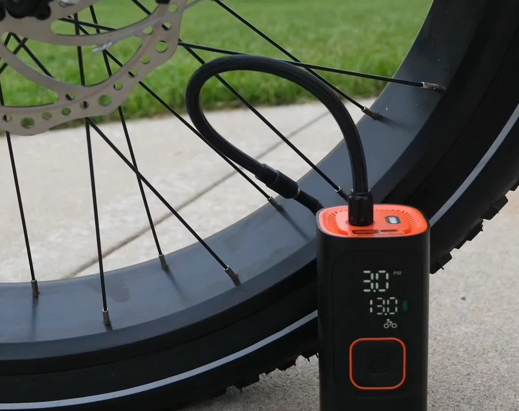 The Skight inflator connected to a bike tire on grass, LCD showing 30 PSI in bicycle mode