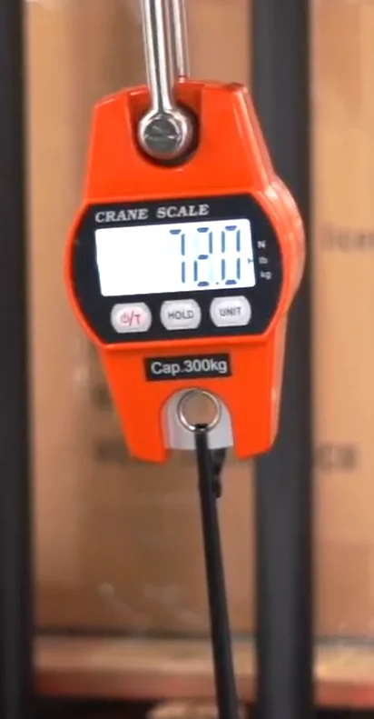 Crane scale reading 72 pounds as a plastic zip tie breaks